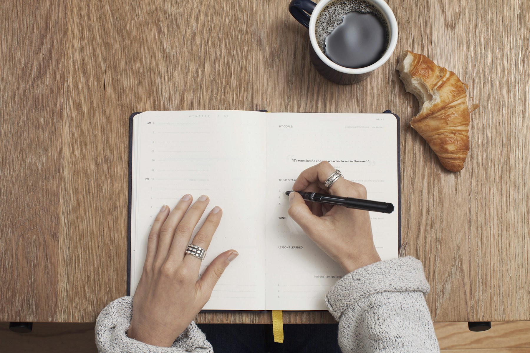 Temporary overhead photograph of a woman writing in an open notebook.